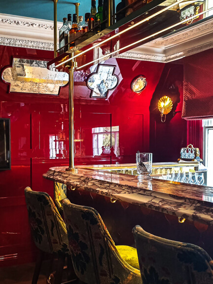 London restaurant design at No 50 Cheyne features a red bar with high gloss walls, blue ceiling, gilded light fixtures, and velvet seating.