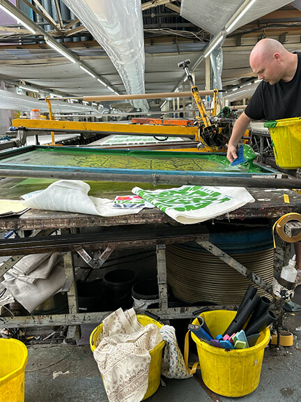 Belfour printed linen fabric in green with ikat pattern being produced in a London textile studio.