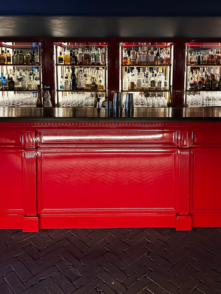 London restaurant design at The Twenty Two in Mayfair featuring a red gloss bar, vintage lighting, and a moody late-night atmosphere.