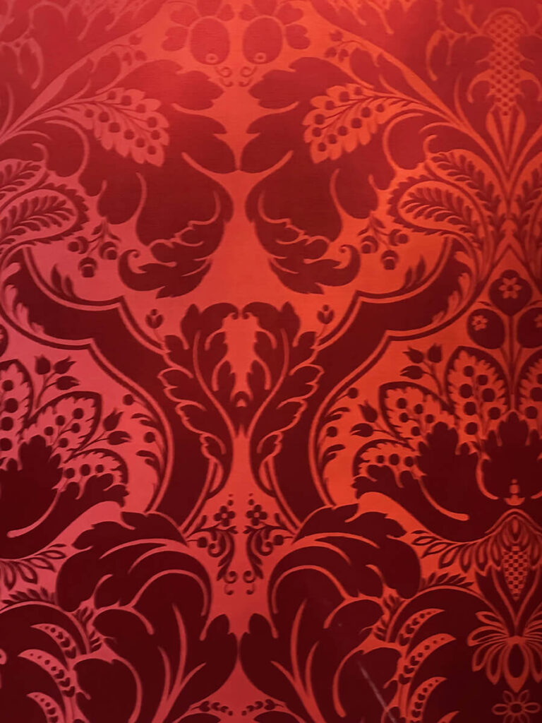Red silk damask wallpaper in a historic New England home, a striking example of Gilded Age Interior Design elegance.