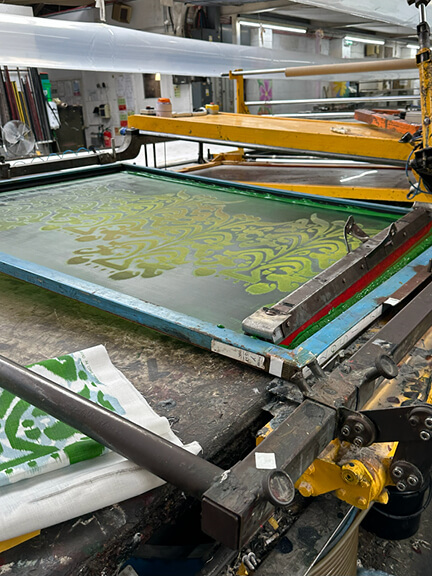 Christopher Farr Cloth Belfour printed fabric in green being screen printed on the machine.