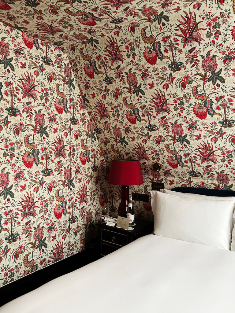 Red floral wallpaper in a guest room at The Twenty Two hotel in London showcasing classic pattern-on-pattern interior design.