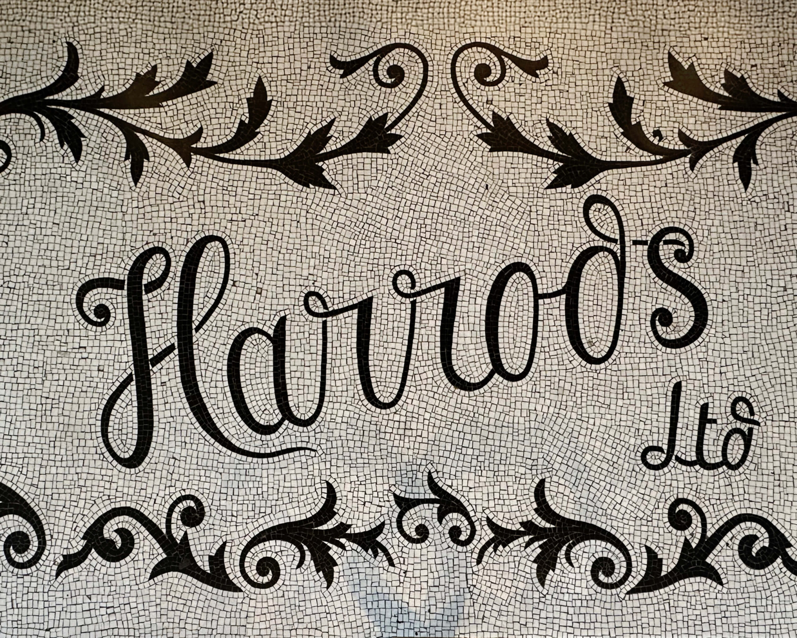 Marble mosaic tile at the main entrance of Harrods London department store showcasing classic black and white craftsmanship.