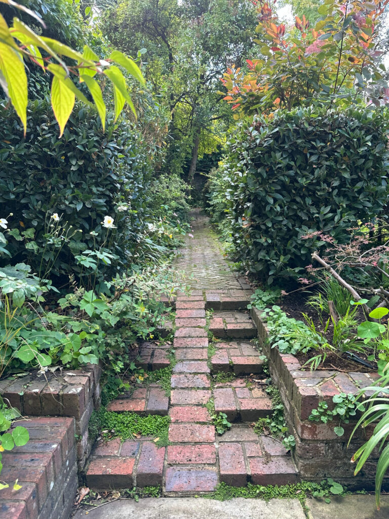 Brick steps and ramp leading to a herringbone garden pathway at a historic home in Holland Park