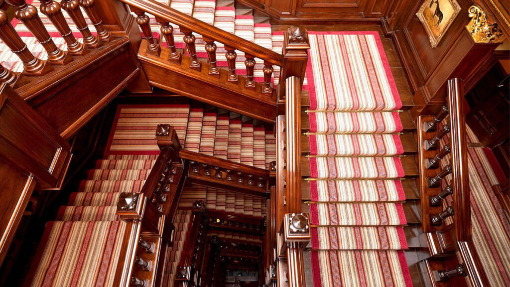 Cool London interior design hotels The Connaught with natural wood millwork and a striped runner, shown in crafted London restaurant design.