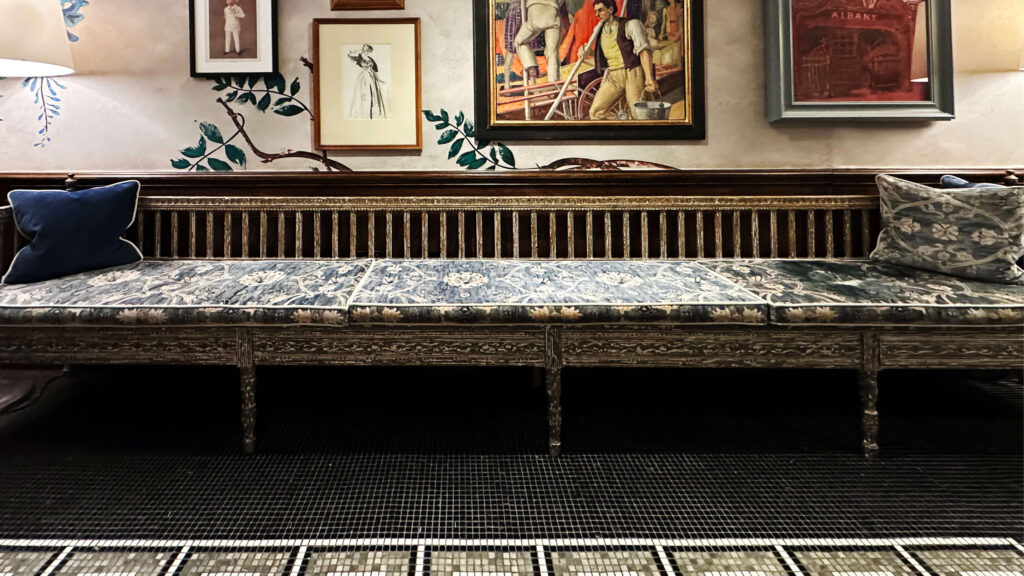 Custom vintage inspired long bench at Brown’s Hotel London with a gallery wall and hand-painted walls, reflecting London restaurant design.