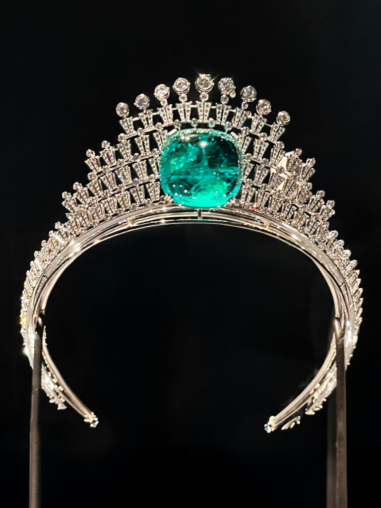 A Cartier tiara featuring a central emerald framed by diamonds displayed in the Cartier Jewelry Exhibit.
