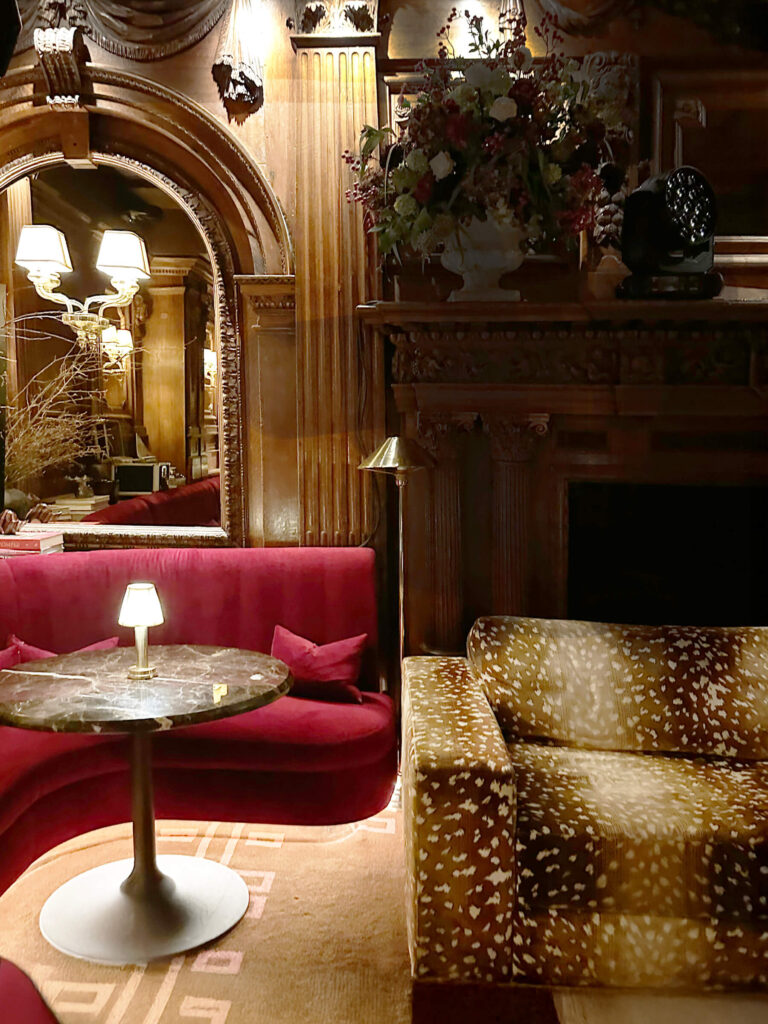 Animal print sofa and red upholstery at cool London private club Tramp with historic woodwork.