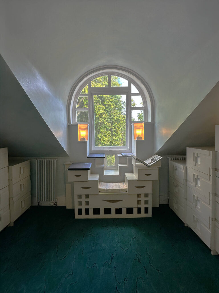 Dark green malachite rug with geometric millwork, white plaster walls, built-ins and desk at the Cosmic House in Holland Park