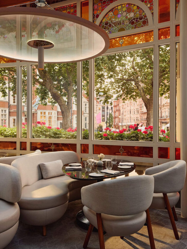 Where to eat London The Connaught custom curved banquettes with a view to the street in a refined cocktail lounge.