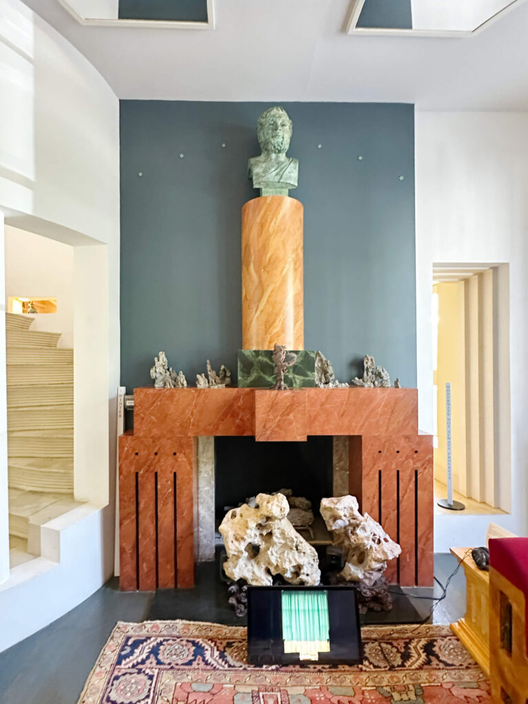 The Cosmic House London living room with an orange marble fireplace and a marble bust in the concept home in Holland Park