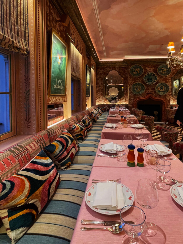 Custom striped banquette and pink decor at cool London private club Oswald’s, a layered look that reflects expressive London restaurant design.