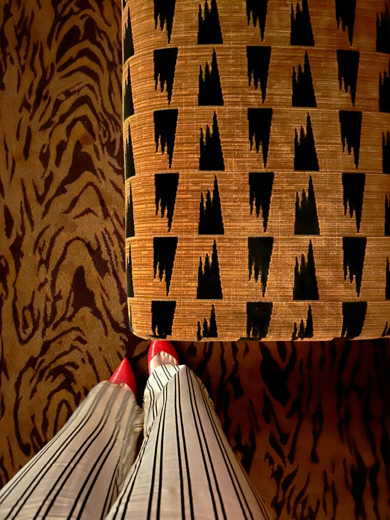 Bold pattern restaurant design in Tramp London with an animal-print carpet and a Pierre Frey upholstered ottoman.