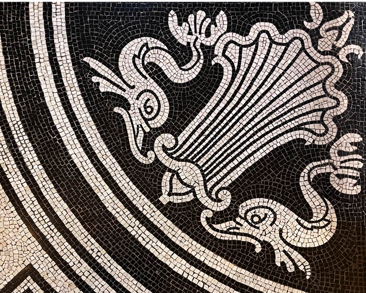 Black and white Victorian mosaic tile flooring with a heraldic-style pattern inside a historic London museum.