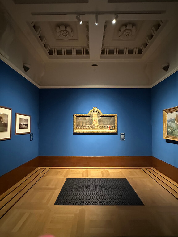 Edwardian Art Buckingham Palace blue-walled gallery room inside the King’s Gallery featuring landscapes and marble busts.