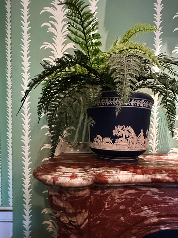 Kensington Palace Interiors featuring green Regency wallpaper paired with a red marble fireplace in a historic room.