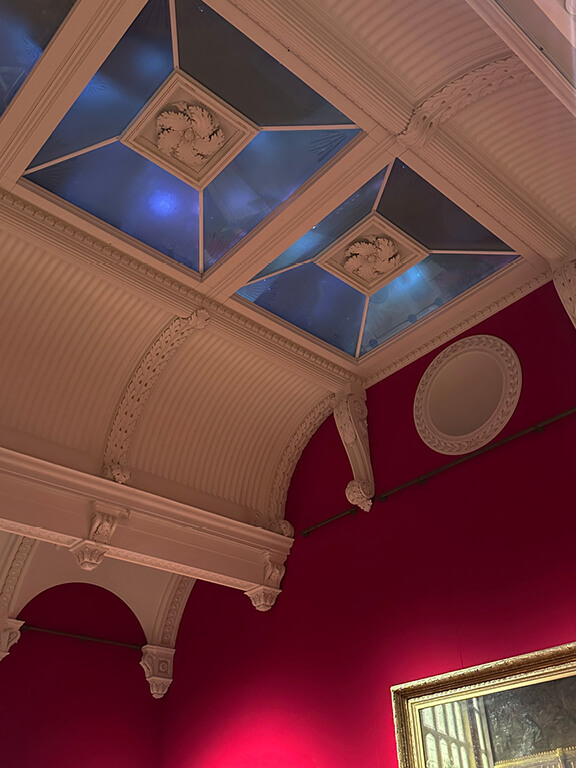 Wide exhibition view inside the King’s Gallery showing framed artworks, display cases, and architectural details.