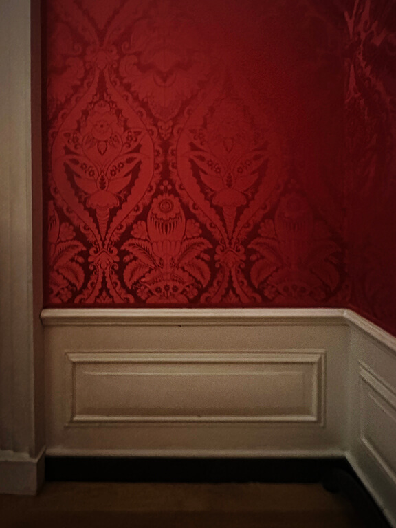 Traditional wainscot paired with red damask defining a formal British interior at Kensington Palace.