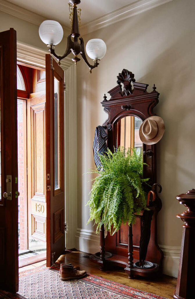 Entryway in a historic Boston brownstone with original light fixture, doors, and vintage rug, designed by Sarah Scales Interior Design Studio.