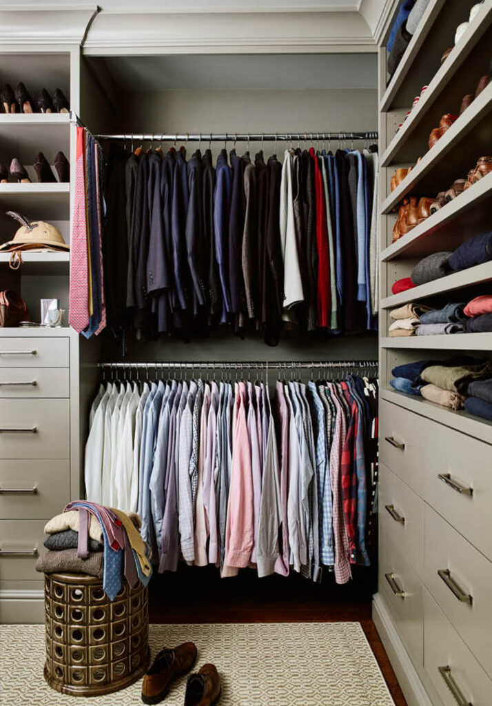 The primary closet features custom light gray cabinets, including open shelves, double hanging space, and drawers for ample storage.