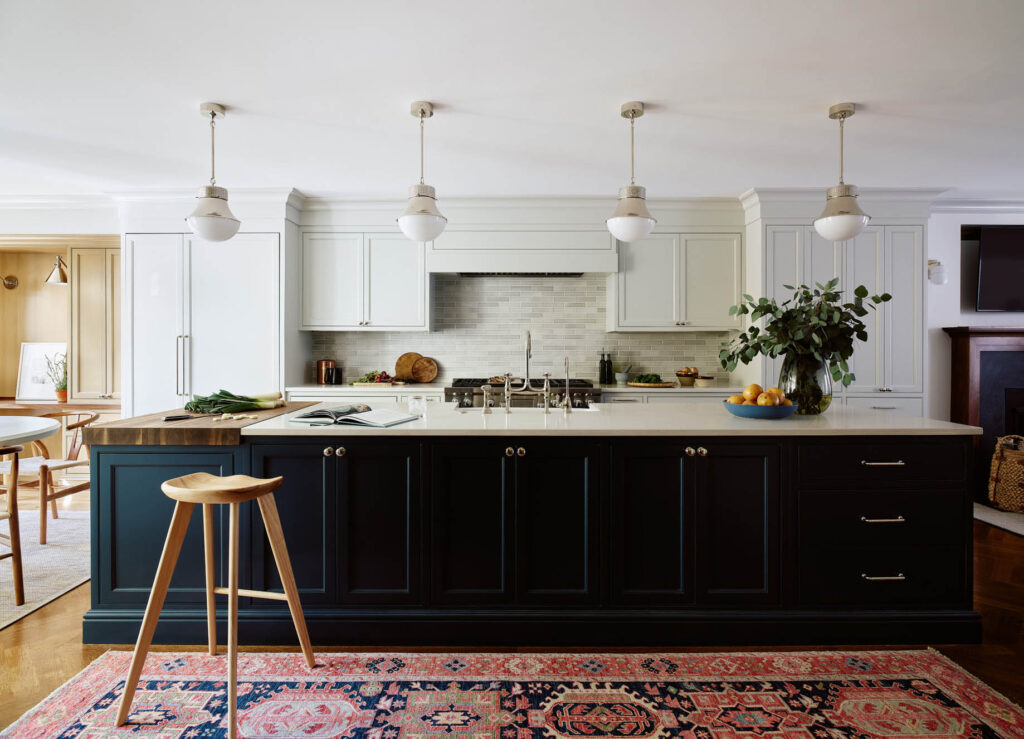 Navy kitchen island, light grey cabinets, artisan backsplash, polished nickel pendants, and mid-century modern furniture in a historic brownstone.