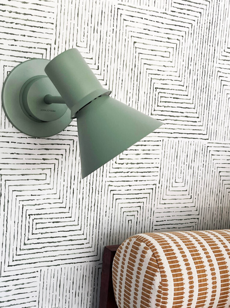 Light green Angelpoise sconce against Kravet green and white geometric wallpaper with yellow upholstery in the basement bunk room.