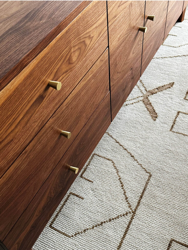 New England-made console in formal dining room with cream and brown tribal motif rug in Vermont mountain home.