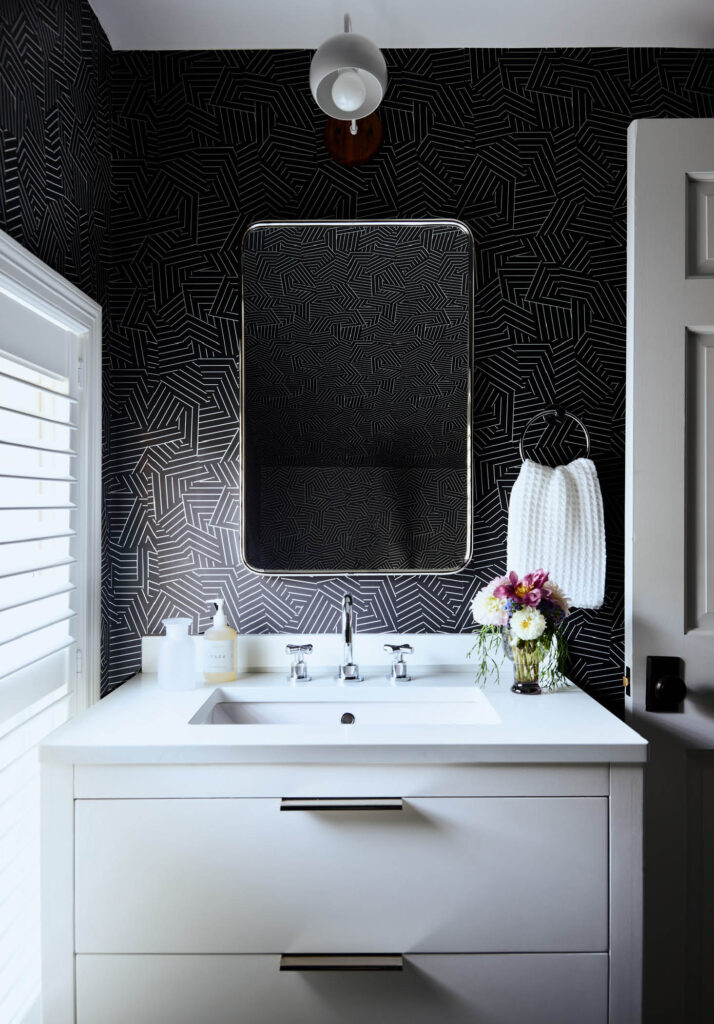 Hingham kids bathroom design with black Kelly Wearstler wallpaper, white vanity, shutters, and white metal sconces. Designed by Boston interior designer Sarah Scales.