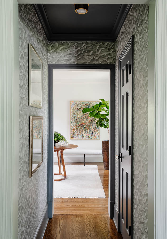 Small corridors - common in historic home design - featuring Cole & Sons Wave wallpaper, offering a view to the foyer and leading to a tucked-away powder room.