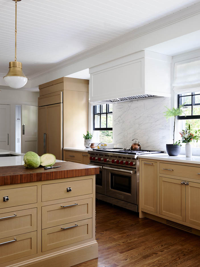 Modern kitchen in historic Hingham home with a white custom range, natural oak cabinets, walnut butcher block counter, brass pendants, and shiplap ceiling.