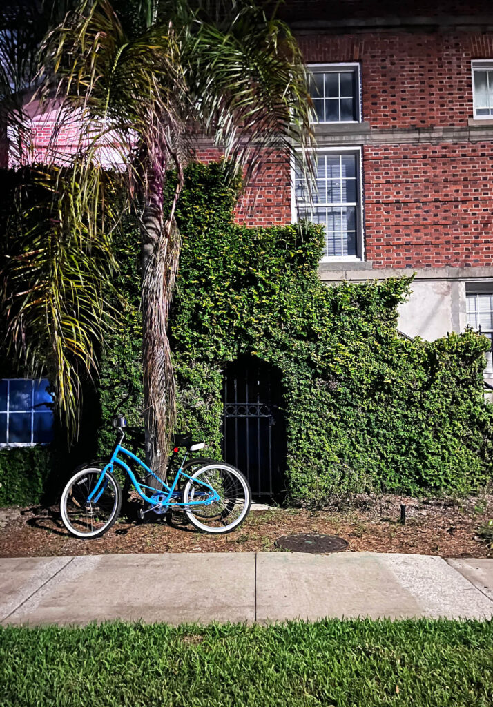 Nighttime photo of a classic building covered in climbing greens with a beach bike perfectly perched in front, captured in St. Augustine, Florida.