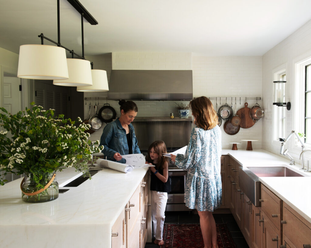 Sarah Scales reviews drawings with clients in a custom Westwood kitchen, showcasing collaborative design and personalized planning.