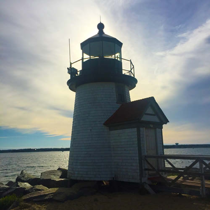 Weathered wood lighthouse on a New England island, surrounded by rocks and overlooking the Atlantic Ocean, inspiring coastal design elements.