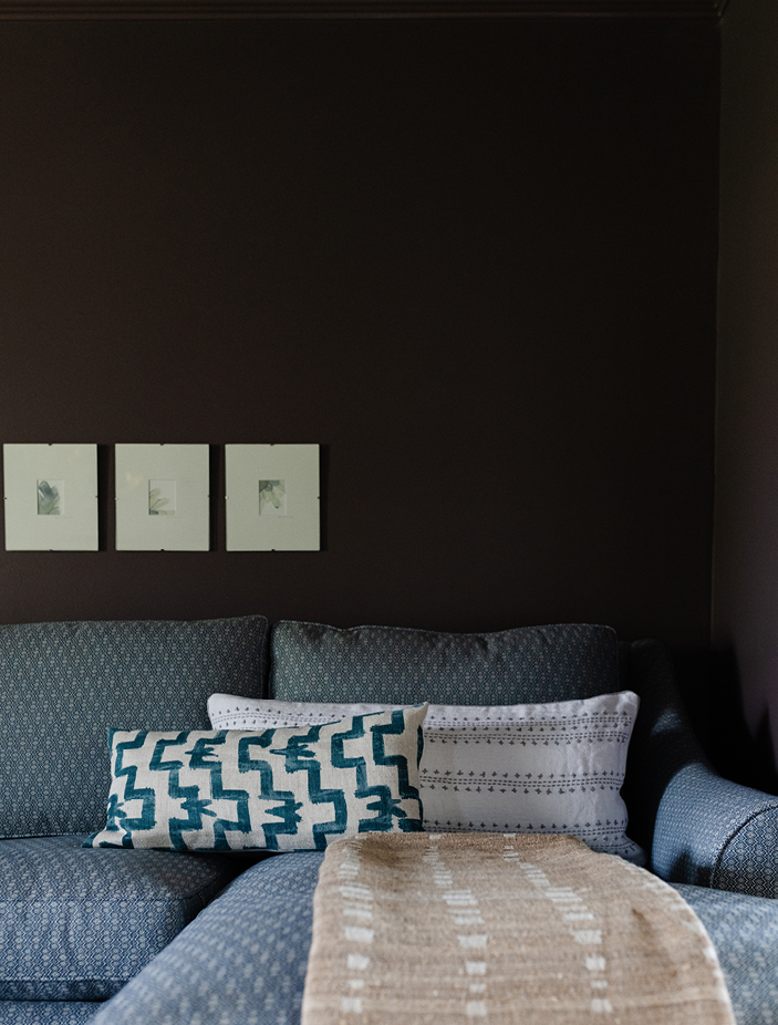 Family room in an Edgartown beach house with dark plum walls, a blue sectional, custom art, and pillows. Designed by Boston interior designer Sarah Scales, this space showcases coastal interior design and New England interior design influences.