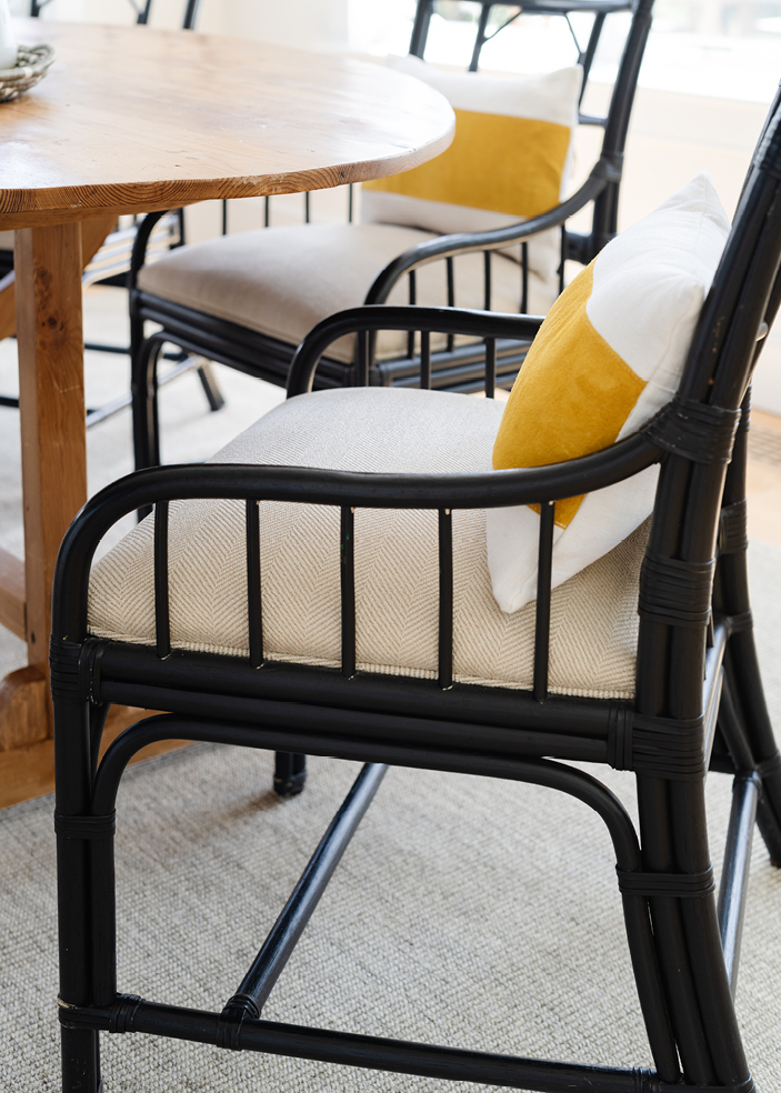 Breakfast nook in an Edgartown beach house featuring custom black wood dining chairs with off-white upholstery, paired with a vintage dining table. Designed by Boston interior designer Sarah Scales, this space blends coastal interior design with New England charm.