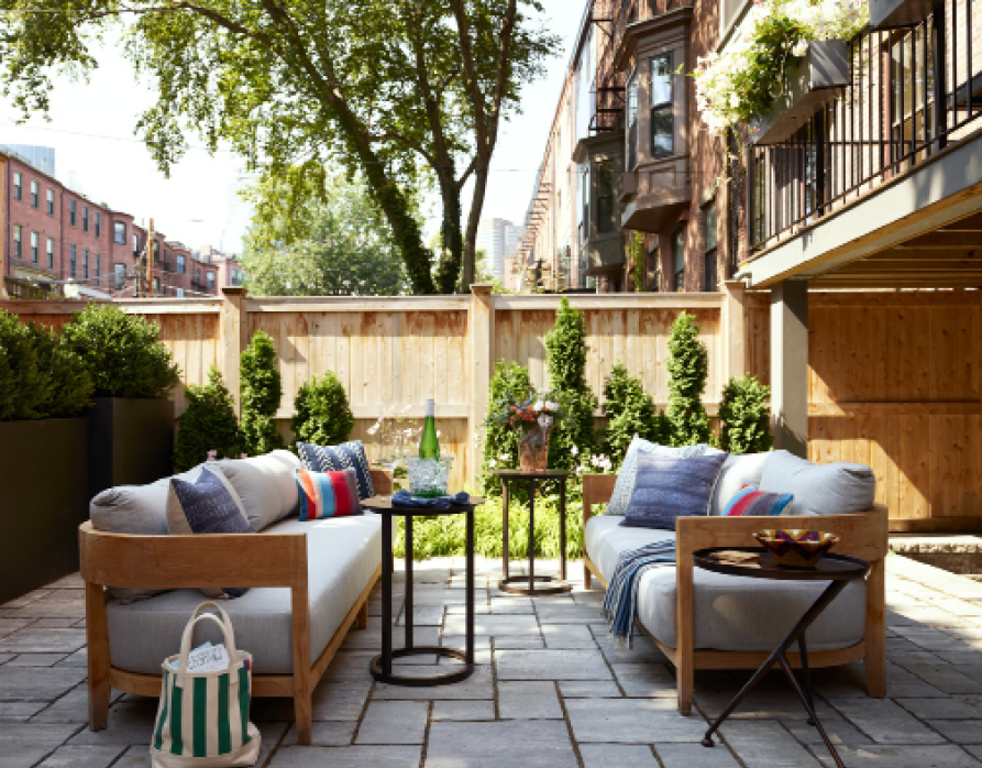 Garden-level patio at a historic Boston brownstone featuring new landscaping, paving, and teak furniture with two facing sofas. Showcasing New England interior design and Boston interior design in an outdoor setting.