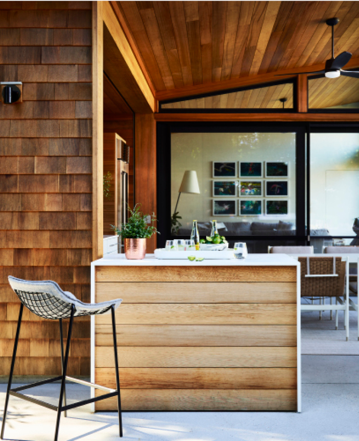 Small bar area with a counter stool at a modern pool house in Hingham, featuring red cedar shingles and modern design elements. 