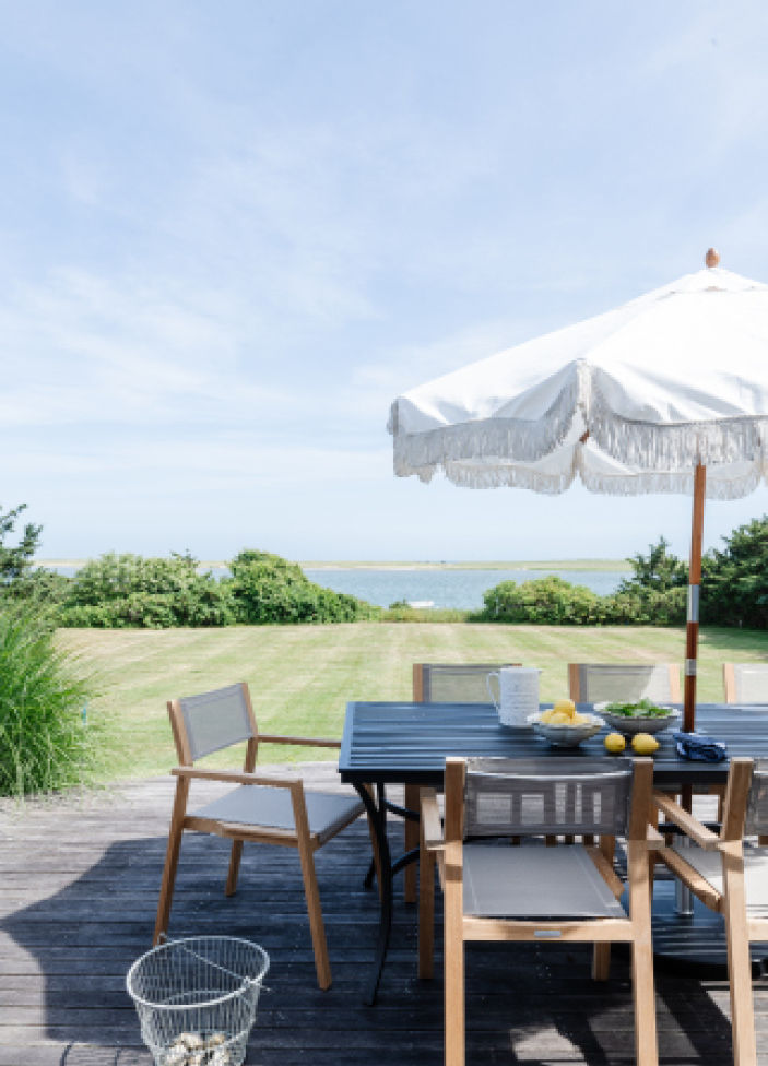 Back deck of an Edgartown waterfront property with stunning views of Katama Bay, designed by a Boston interior designer to enhance outdoor living.