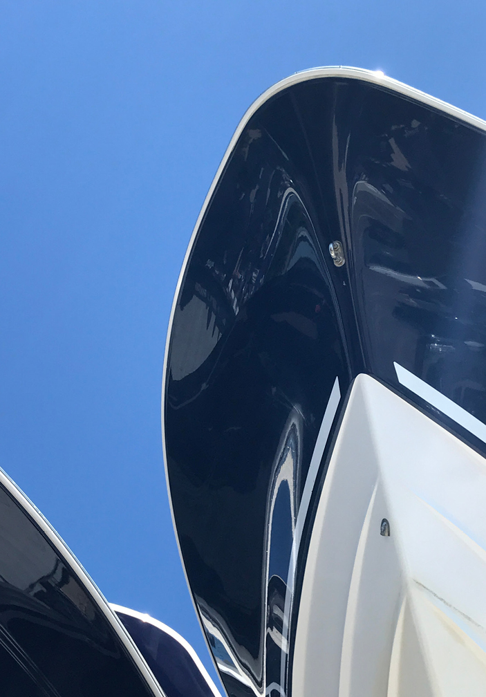 Boat hulls in Falmouth, featuring bold navy and white stripes under bright blue skies, offering timeless inspiration for a Boston interior designer’s New England design palette.