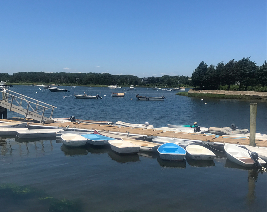 Falmouth Harbor boat docks with a simple dinghy in shades of white, beige, and blue, capturing the essence of summer in New England design.