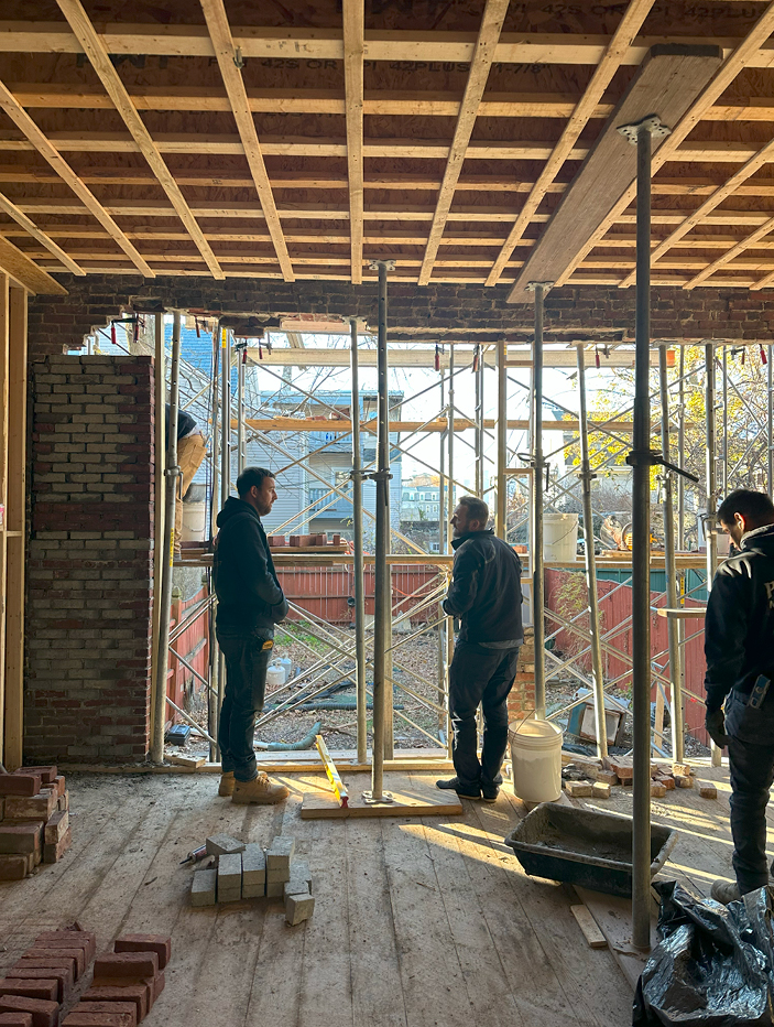 Architect Owen Thomas and builder Gareth Barr on-site during a historic Boston brownstone renovation, working on a new opening for floor-to-ceiling doors.