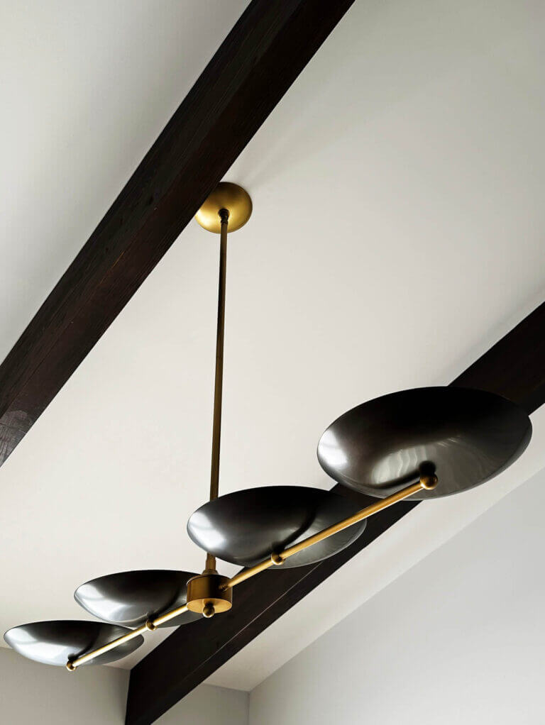 An Arteriors Griffith linear pendant with a wood ceiling and white walls in a Vermont new construction home. Designed by Boston interior decorators.