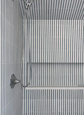 Attic bathroom in a Boston South Shore beach house with a blue and white striped shower, designed by a Boston interior design firm.