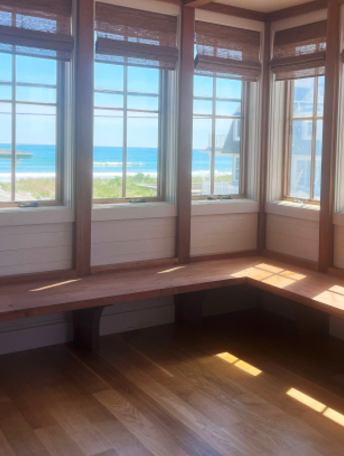 Sunroom with custom millwork, fir beams, a custom bench, and white shiplap, overlooking the ocean in a Boston South Shore home.