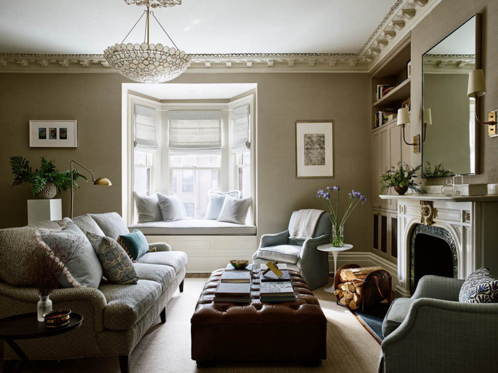 Family room in a classic brownstone with grasscloth walls, custom furniture, leather ottoman, and original marble fireplace by a Boston historic home designer.