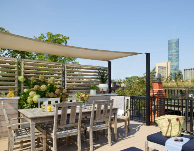 South End roof deck with custom shade sail, teak furniture, dining table, chaise loungers, and Boston skyline views by top Boston designers.