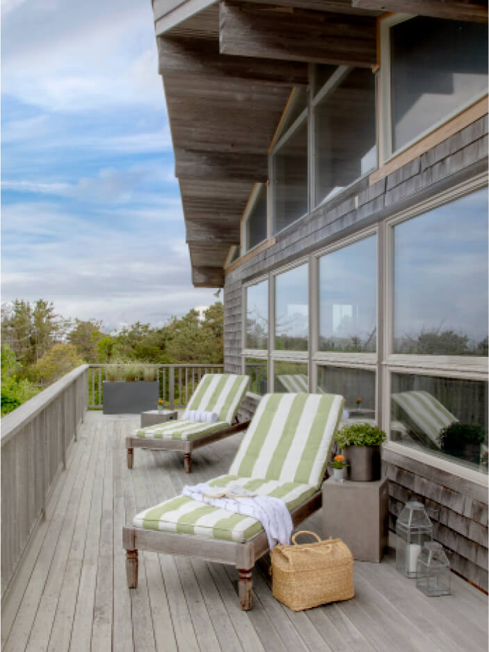 Deck at Martha’s Vineyard home with loungers and green-and-white striped cushions, designed by a Cape Cod interior designer.