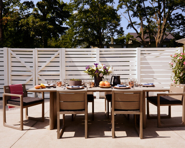 Outdoor dining area with Restoration Hardware furniture, black cushions, and a dining table at a historic Hingham home by Hingham interior decorators.