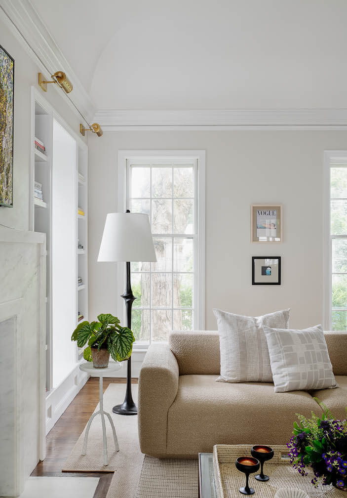 Light grey living room with vaulted ceilings, modern marble fireplace, and Scandinavian sofa in a historic Hingham home by a top Boston interior designer.