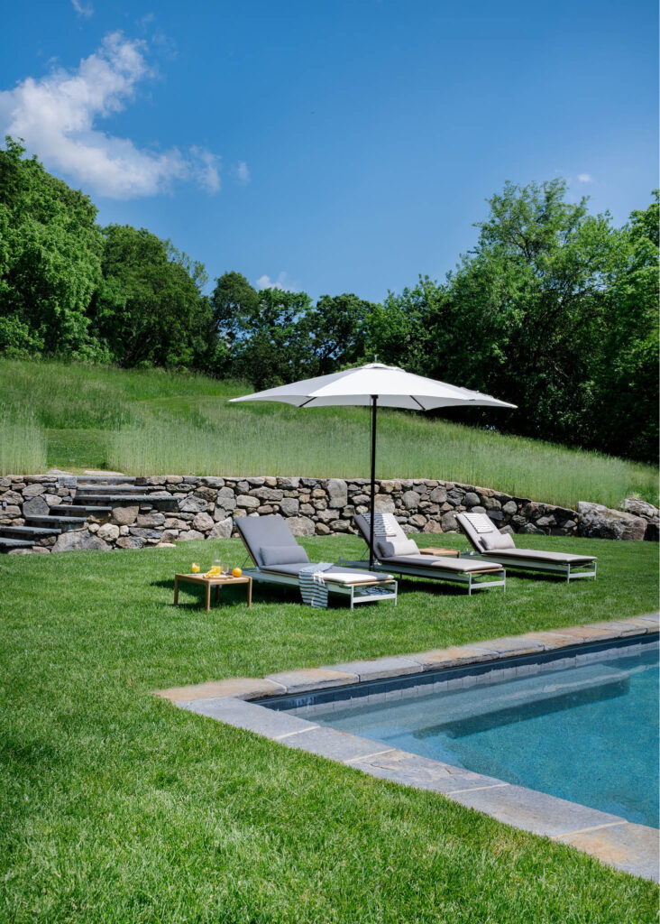 Modern pool at a historic Concord home with sleek outdoor furniture, selected by interior decorators in Boston for modern outdoor living.